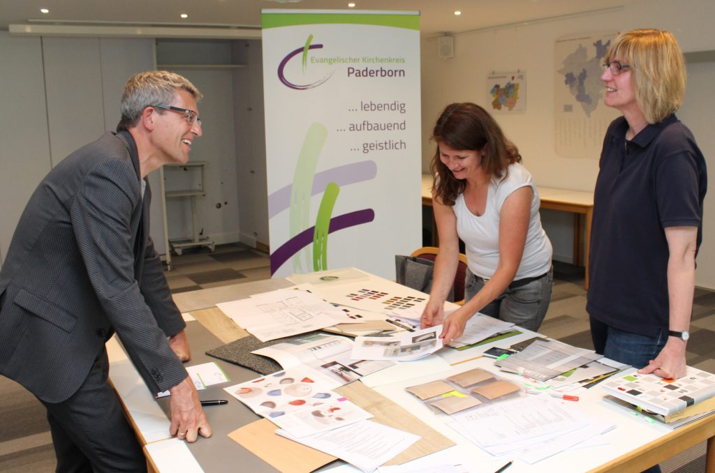 Sichten Materialien für die Innensanierung: Superintendent Volker Neuhoff (v. l.), Innenarchitektin Sabine Schütte (Helle Freude, Büro für Raumkonzepte, Paderborn) und Architektin Sigrid Bartscher (Evangelisches Kreiskirchenamt Gütersloh-Halle-Paderborn). Foto: EKP/Oliver Claes