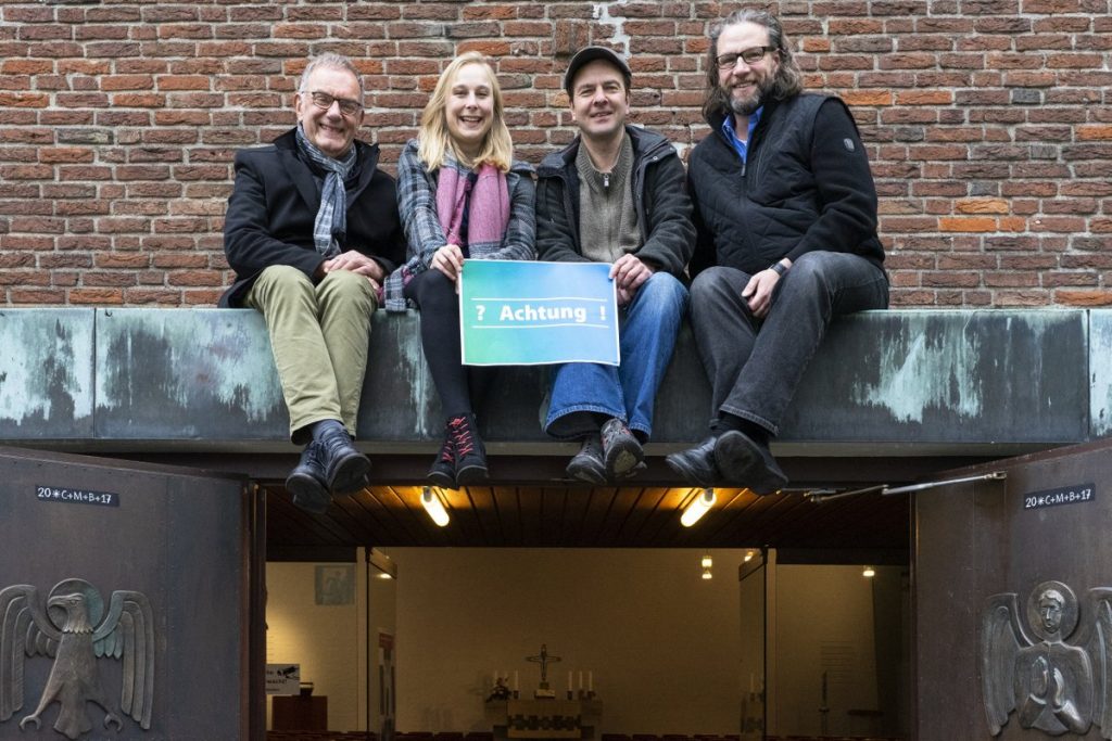 In luftiger Höhe über der Tür zur Christus-Kirche wird zur Kulturnacht Schloß-Neuhaus eingeladen: vom Theater Paderborn Gesa Köhler und Alexander Wilß (Mitte) sowie die Veranstalter Hans-Georg Hunstig (links) und Pfarrer Oliver Peters (rechts). Foto: Tobias Vorwerk