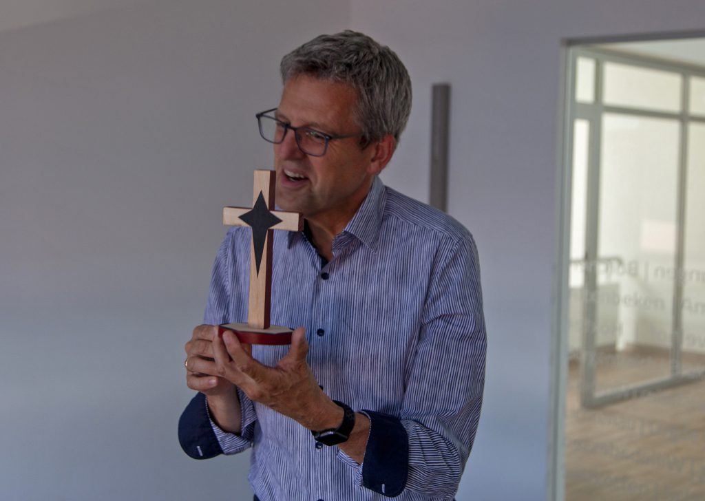Gastgeschenk: Superintendent Volker Neuhoff mit einem Holzkreuz, das ihm sein Kollege Frederick Muganyizi geschenkt hat. Foto: Wolfgang Dzieran