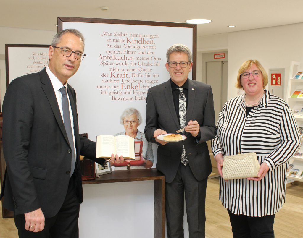 Ausstellungseröffnung: Ulf Schlüter, Vizepräsident der Evangelischen Kirche von Westfalen (v. l.), Volker Neuhoff, Superintendent des Evangelischen Kirchenkreises Paderborn und Elke Hansmann, Diakoniepfarrerin des Kirchenkreises, mit Erinnerungsstücken aus einem „Schatzkästchen des Lebens“ in der Ausstellung „Was bleibt.“. Foto: EKP/Oliver Claes