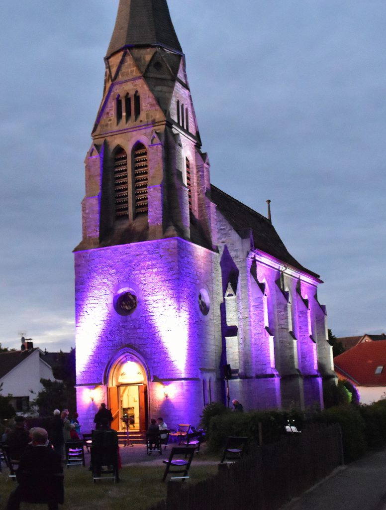 Farbenfroh: Mit einer Andacht vor der Nieheimer Kreuzkirche wurde das Pfingstfest eingeläutet. Die Fassade der Kirche war durch ein Beleuchtungskonzept in buntes Licht gehüllt. Foto: Heinz Wilfert