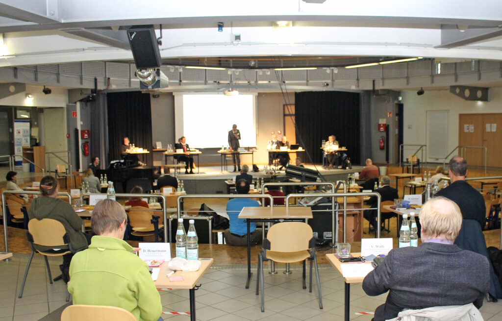 Synode unter Corona-Bedingungen: Mit dem nötigen Abstand zwischen den Teilnehmenden konnte die konstituierende Sitzung der Synode des Evangelischen Kirchenkreises Paderborn in der großen Mensa der Friedrich-Spee-Gesamtschule Paderborn stattfinden. Für die Unterstützung bei der Organisation dankte Superintendent Volker Neuhoff der Stadt Paderborn, Schulleiter Lothar Schlegel und den hilfreichen Mitarbeitenden von Schule und Kirchenkreis. Foto: EKP/Oliver Claes