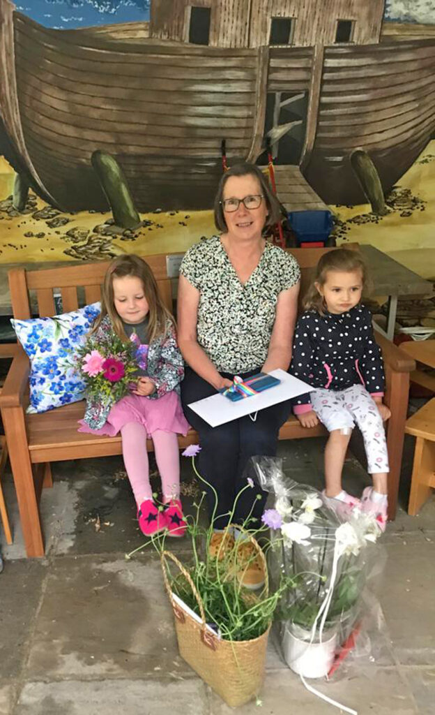 Abschiedsgeschenk: Monika Schuler auf der neuen Bank mit Clara und Sophia. Foto: Arche Warburg