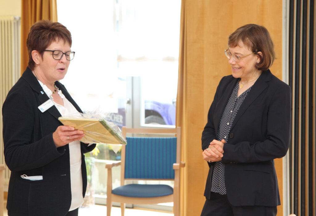 Einrichtungsleiterin Heidemarie Hellwig überreicht Präses Annette Kurschus das „Bewohnermärchen: Der goldene Rollator“. Foto: EKvW