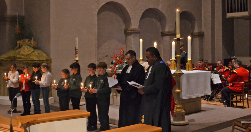 Schüler der Grundschulen Luther (weiß) und Attenborough (grün) mit Pfarrer Dr. Eckhard Düker und Rev. Josefa Mairara im Christingle-Familiengottesdienst.Foto: Abdinghof-Bezirk 