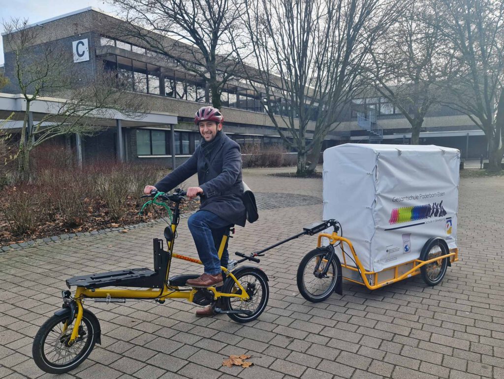 Pfarrer Klemme auf Übungsfahrt mit dem Elektro-Lastenrad des Fördervereins der Gesamtschule Elsen auf dem Schulhof. Damit soll das Essen zum evangelischen Gemeindehaus gebracht werden.Foto: S. Beer