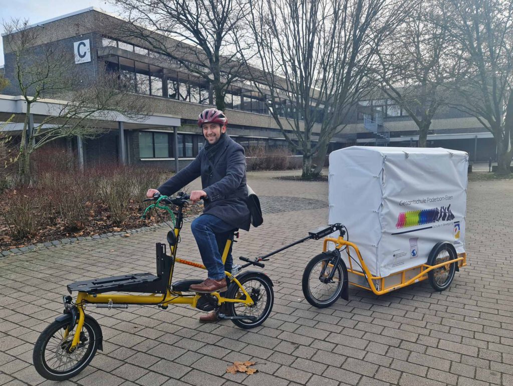 Pfarrer Klemme auf Übungsfahrt mit dem Elektro-Lastenrad des Fördervereins der Gesamtschule Elsen auf dem Schulhof. Damit soll das Essen zum evangelischen Gemeindehaus gebracht werden.Foto: S. Beer 