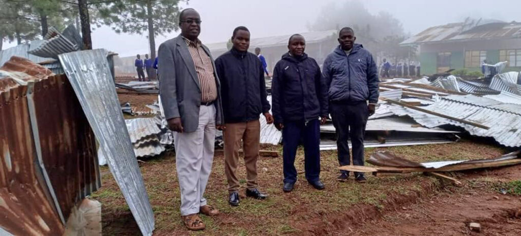 In der beschädigten Schule: District Pastor Frederick Muganyizi, (l.) mit Lehrern der Karambi Secundary School. Foto: Kirchenkreis Kusini B