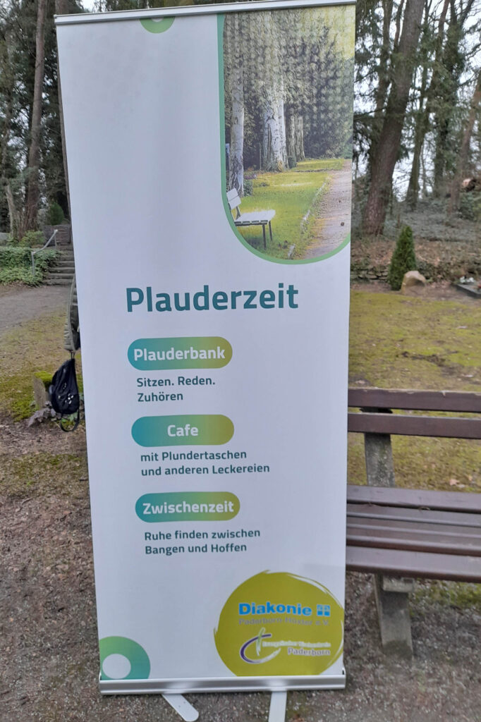 Aufsteller weisen den Weg: Zu finden ist die „Plauderbank“ inklusive Pavillon am Ende des Hauptweges auf dem Waldfriedhof, direkt vor der großen Kreuzigungsgruppe (Friedhofskreuz).Foto: RAUS-GRUPPE 