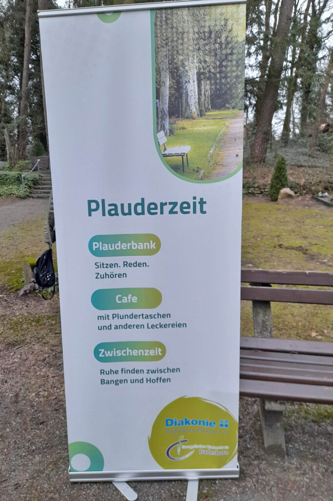 Aufsteller weisen den Weg: Zu finden ist die „Plauderbank“ inklusive Pavillon am Ende des Hauptweges auf dem Waldfriedhof, direkt vor der großen Kreuzigungsgruppe (Friedhofskreuz).Foto: RAUS-GRUPPE 