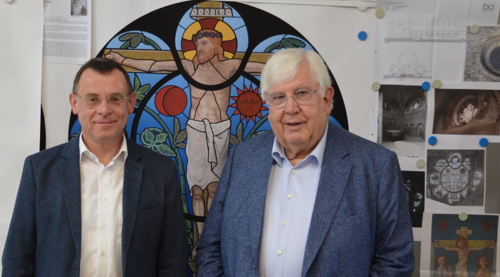Pfarrer Dr. Eckhard Düker (v. l.) und Dr. Joachim Mohn vor dem Entwurf für das südliche Glasfenster im Chorraum.Foto: Abdinghof-Bezirk