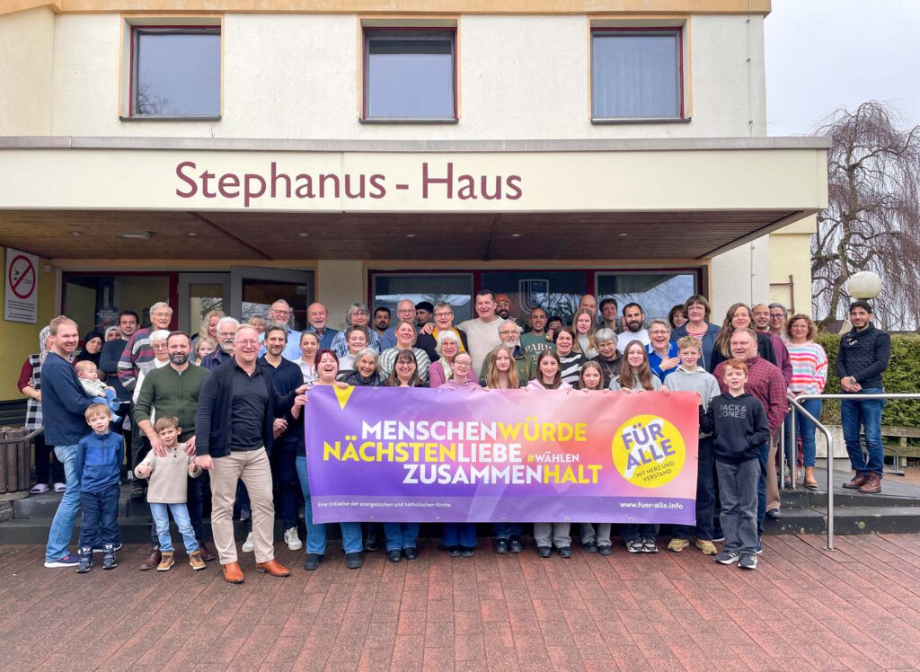  Menschen in der evangelischen Kirchengemeinde Borchen mit dem Banner der Initiative "Für alle".