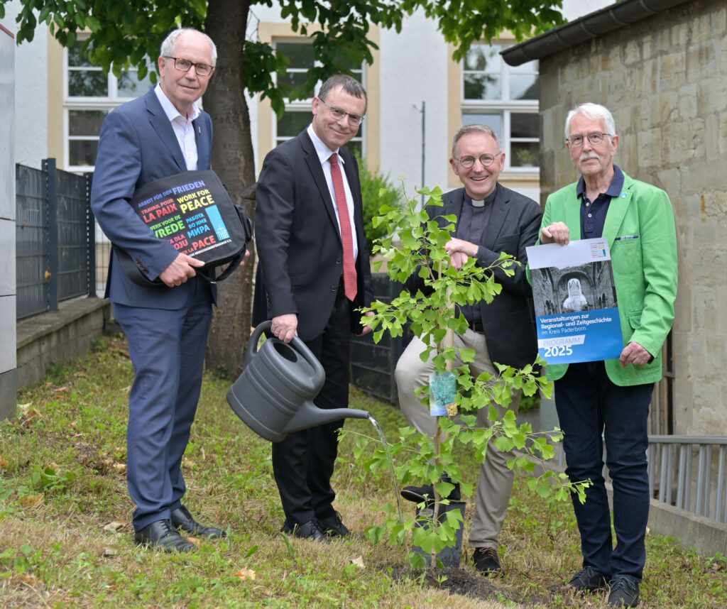 Beteiligte pflanzen einen Baum zur Erinnerung an einen ökumenischen Friedensgottesdienst.