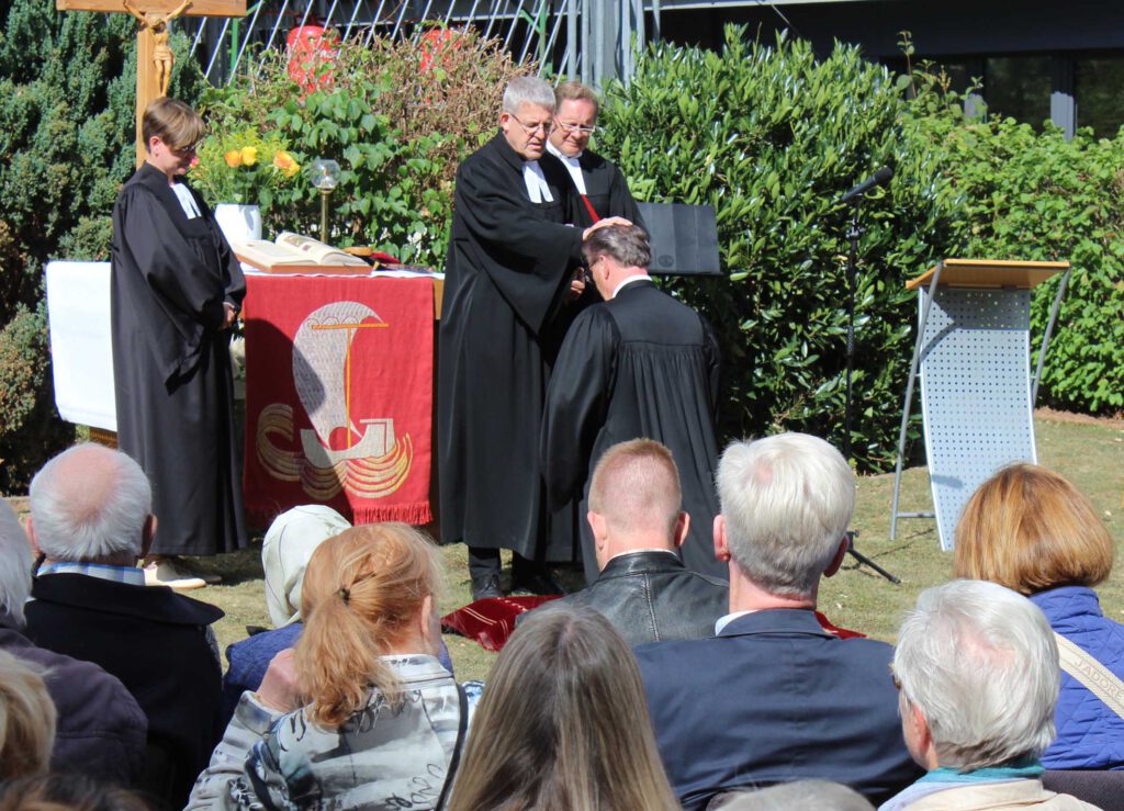 Frank Schubert kniet und Superintendent Volker Neuhoff legt ihm die Hände auf.