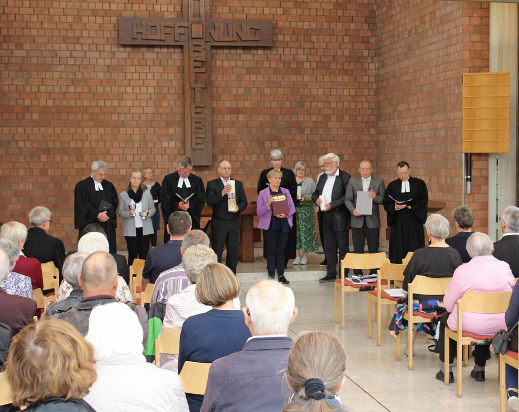 Mitglieder und Pfarrer der Kirchengemeinde Paderborn mit liturgischen Gegenständen am Altar im Martin-Luther-Zentrum.
