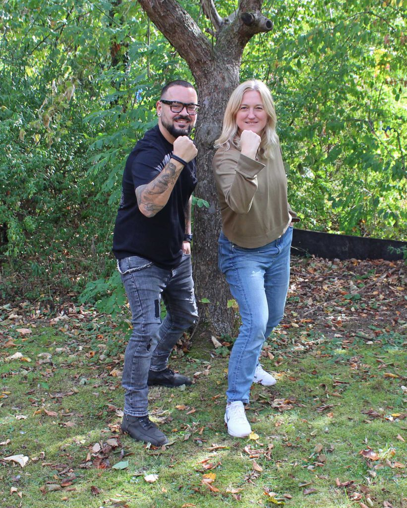 Die Leiterin und der Teamer der Vater-Sohn-Freizeit stehen auf einer Wiese unter einem Baum.