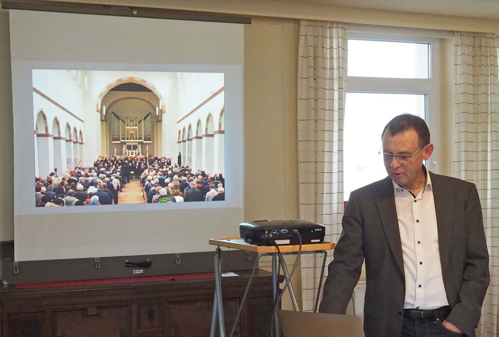 Referent Pfarrer Dr. Eckhard Düker zeigt auf einer Leinwand Bilder aus der Geschichte der Abdinghofkirche.