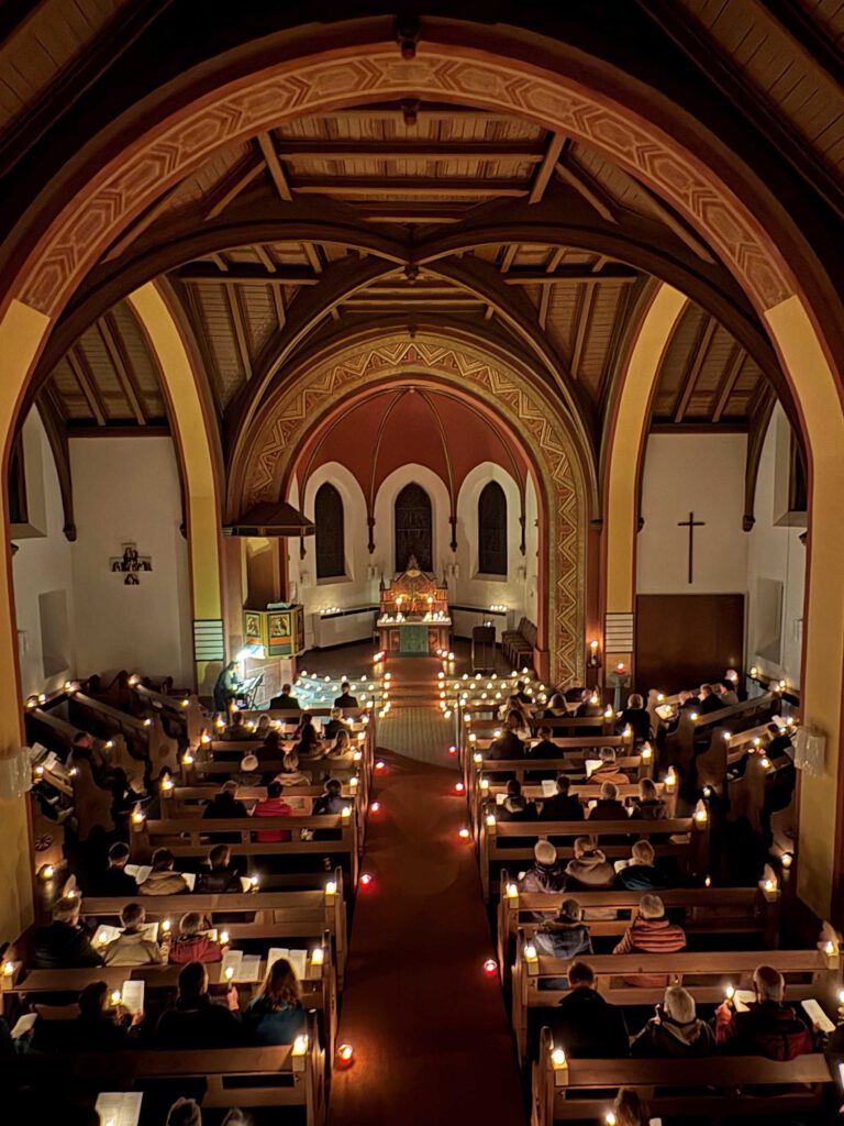 Besucherinnen und Besucher des Gottesdienstes in der mit Kerzen beleuchteten evangelischen Kirche in Steinheim.