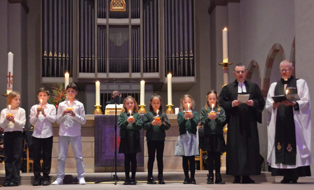 Schulkinder und Pfarrer im Altarraum der Abdinghofkirche.