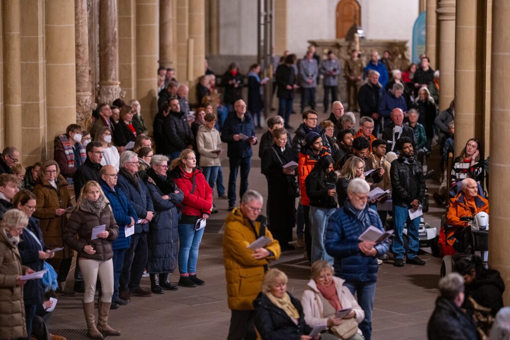 Besucherinnen und Besucher des Gottesdienstes stehen im Seitenschiff des Paderborner Domes.