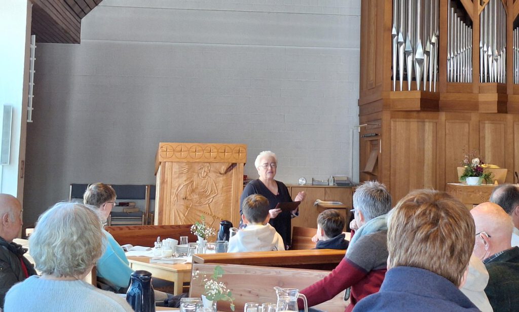 Ein Person steht an einem Kaffeetisch in der Kirche und spricht.