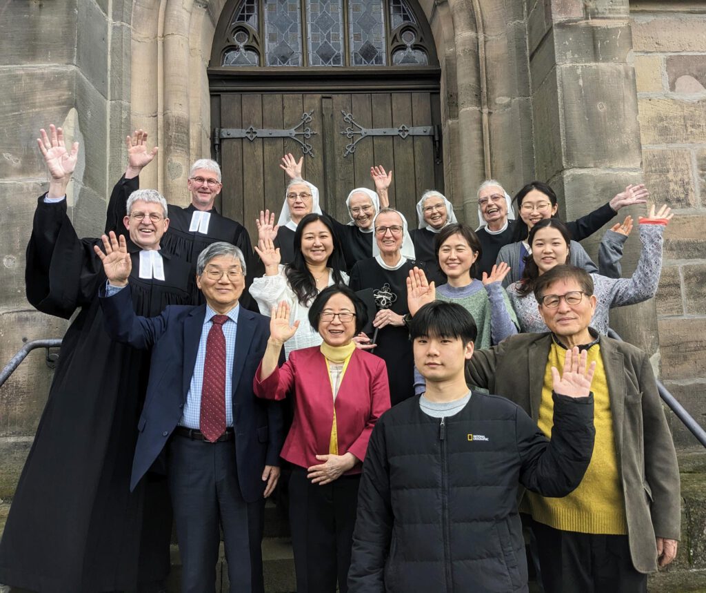 Beteiligte Personen stehen vor einer Kirchentür und winken.
