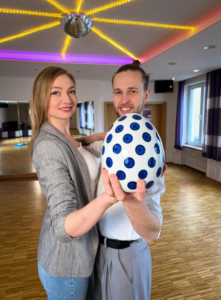 Ein Tanzpaar hält ein Osterei in den Händen.