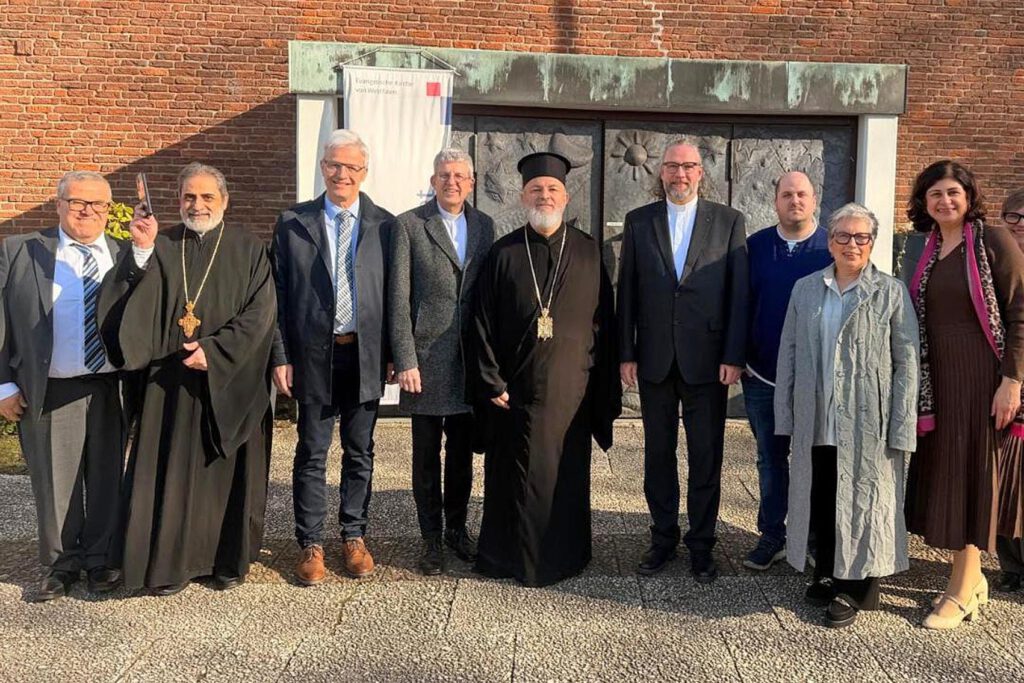 Eine Gruppe Menschen steht vor der Eingangstür einer Kirche.