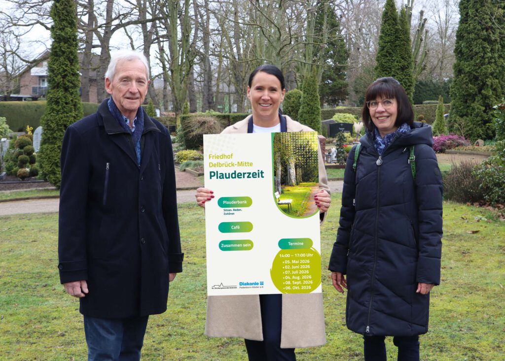 Menschen mit einem Plakat in Händen auf einem Friedhof.