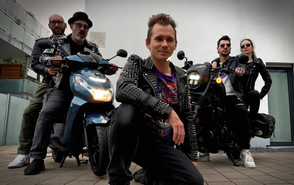 Musikerinnen und Musiker sitzen auf und vor Motorrädern.