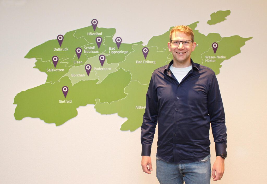 Ein Mann steht vor einer Wandkarte, die den Evangelischen Kirchenkreis Paderborn zeigt.