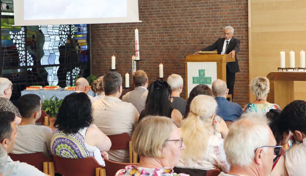 Menschen in einer Kirche hören einem Redner zu.