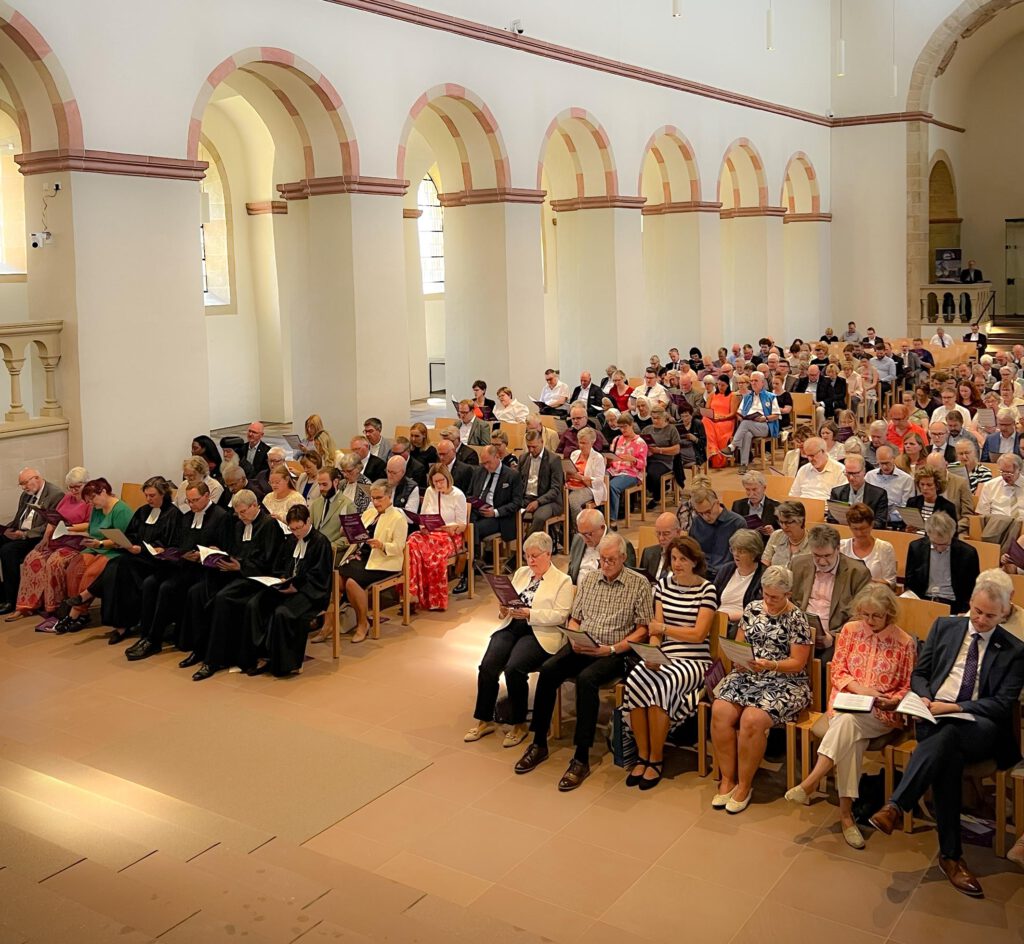 Menschen sitzen bei einem Gottesdienst in einer historischen Kirche.