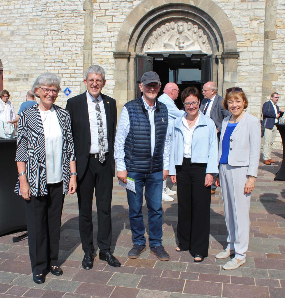 Drei Frauen und zwei Männer stehen vor dem Eingang einer Kirche.