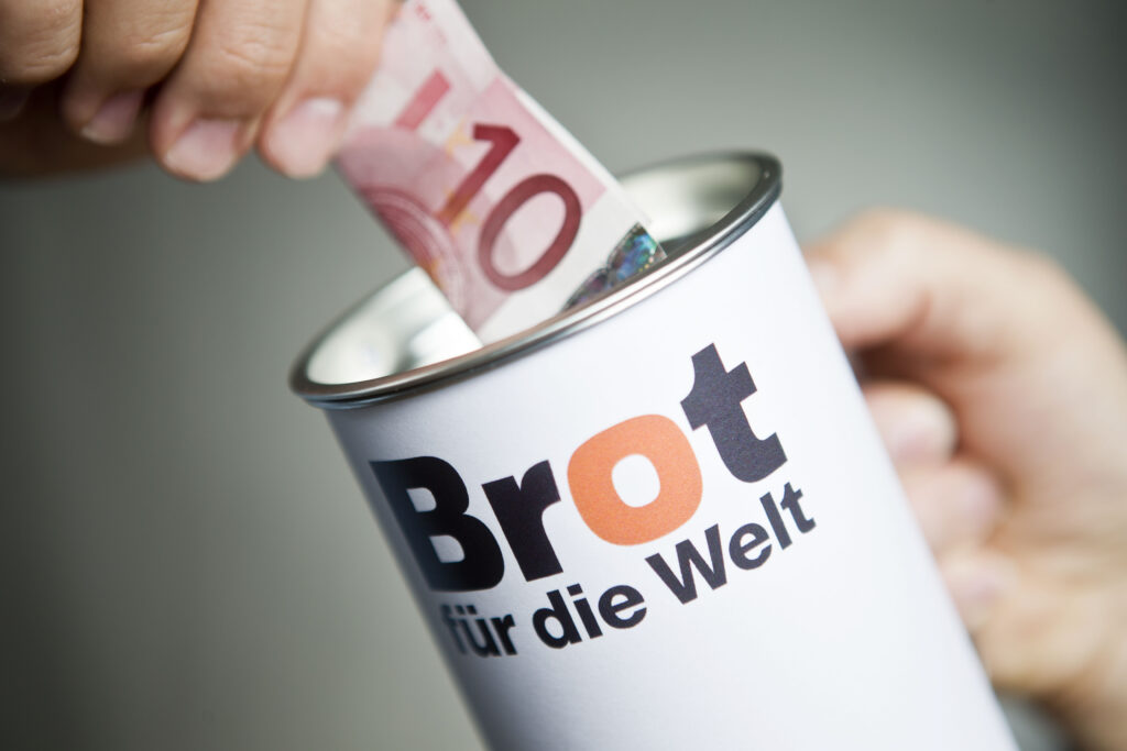 Spendendose von Brot für die Welt und einem Geldschein.