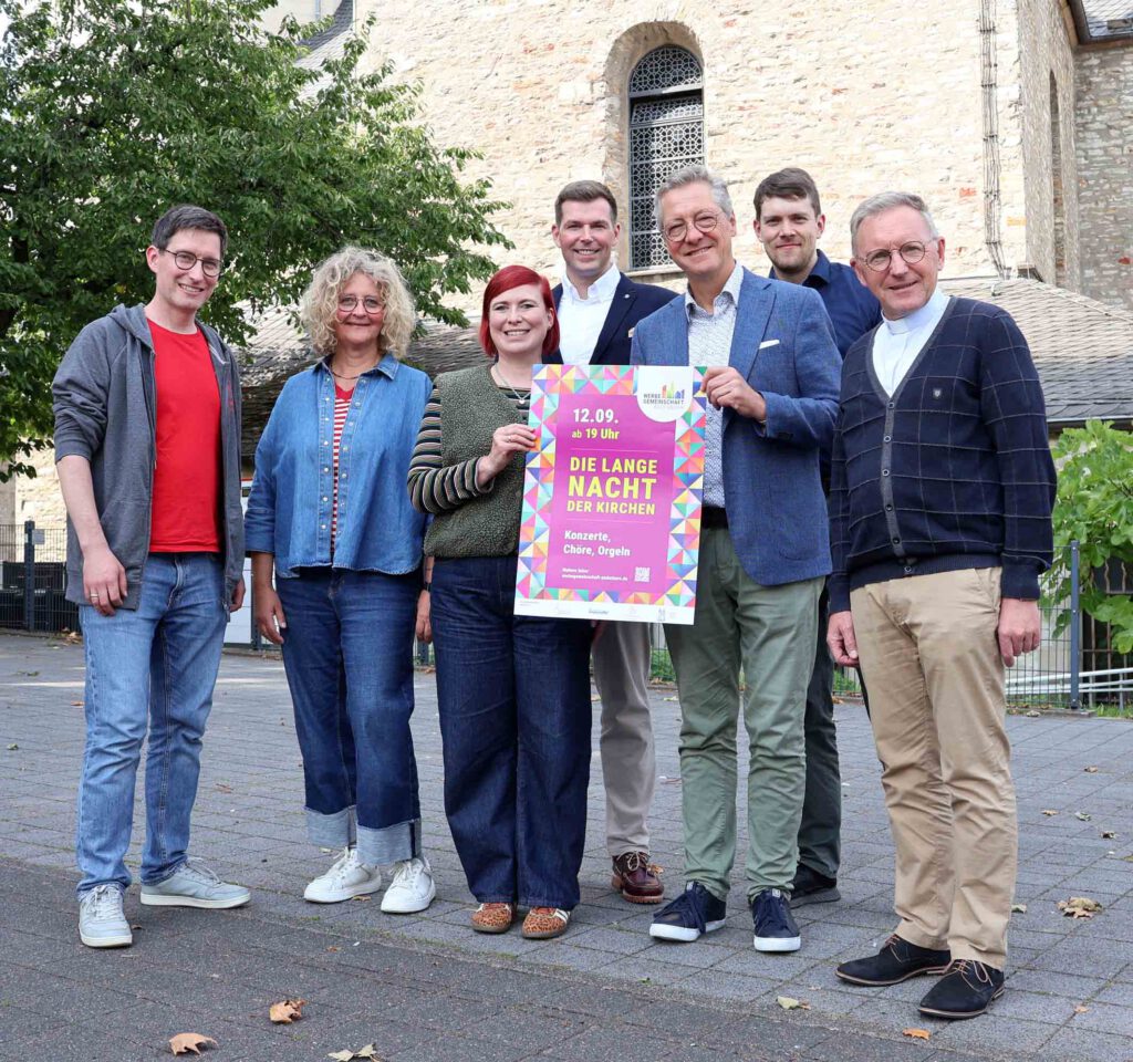 Eine Gruppe Menschen hat sich vor einer Kirche aufgestellt, eine Person hält ein Plakat in den Händen.