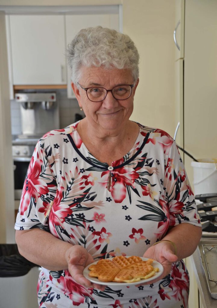 Eine Frau hält einen Teller mit Waffeln in der Hand.