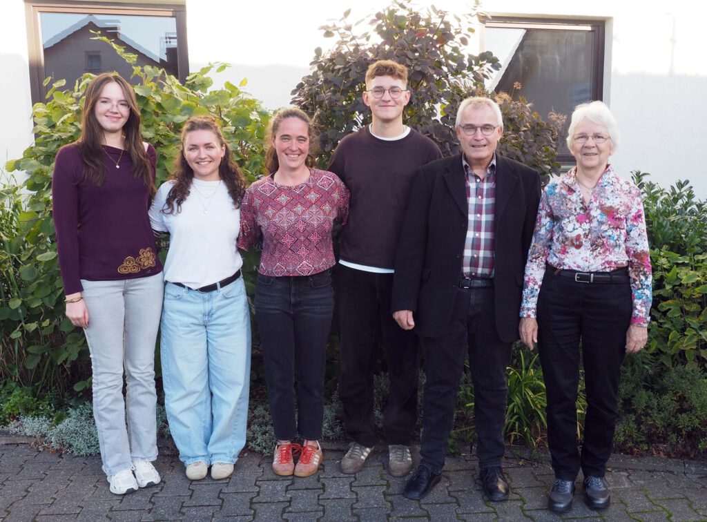 Eine Gruppe von Menschen hat sich vor einem Gebäude für das Foto aufgestellt.